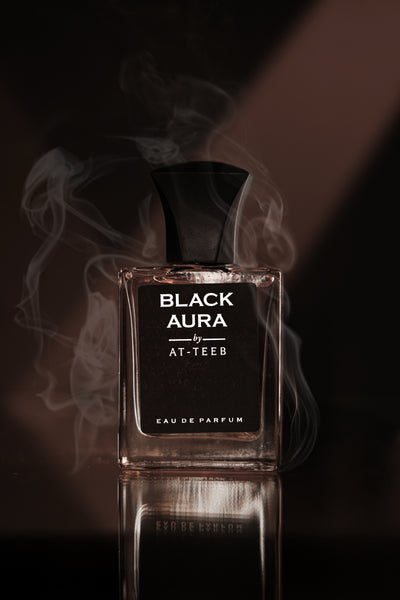 Eau de parfum glass bottle with BLACK AURA label, amber liquid visible.