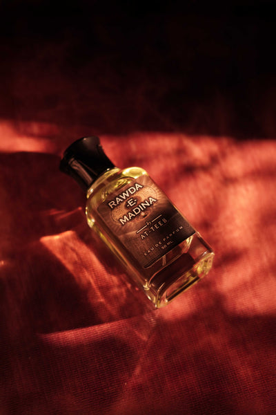 RAWDA-E-MADINA perfume bottle, amber glass with black cap, label facing up