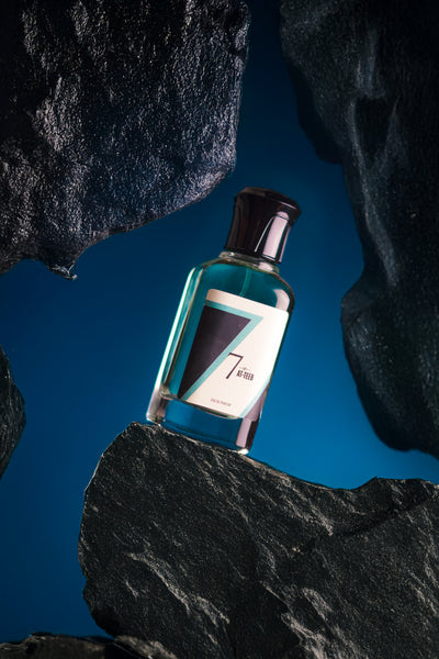 Perfume bottle with teal liquid, clear glass, silver cap, white label with 7