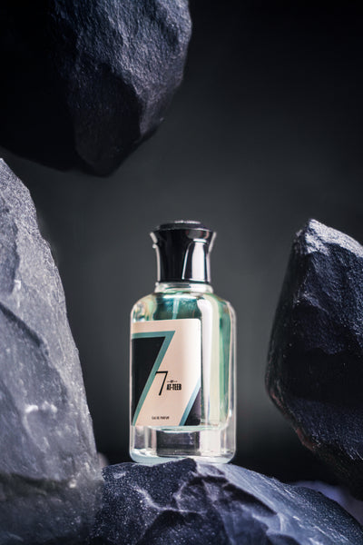 Perfume bottle with teal liquid, clear glass, silver cap, white label and 7