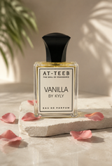Vanilla eau de parfum bottle with black cap, golden liquid, surrounded by rose petals